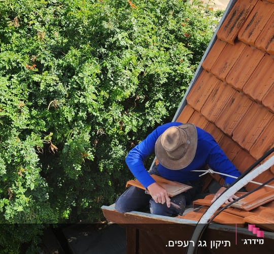 אדם עובד על גג רעפים עם כובע רחב שוליים